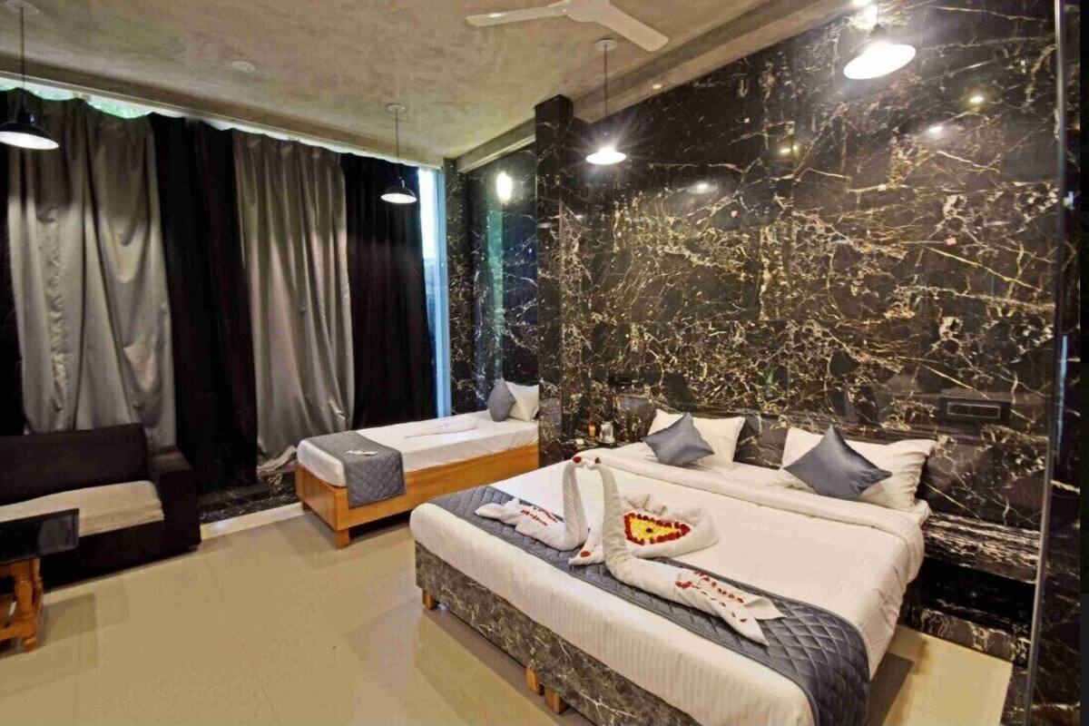 Une chambre d’hôtel avec un mur en marbre, deux lits, un canapé et un bureau.