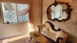 A room with a sofa, a table, a mirror, and a window with curtains.