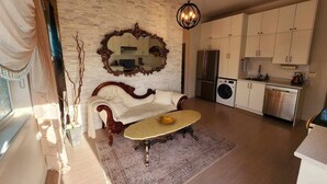 A living room with a sofa, a coffee table, a large mirror, and a chandelier.