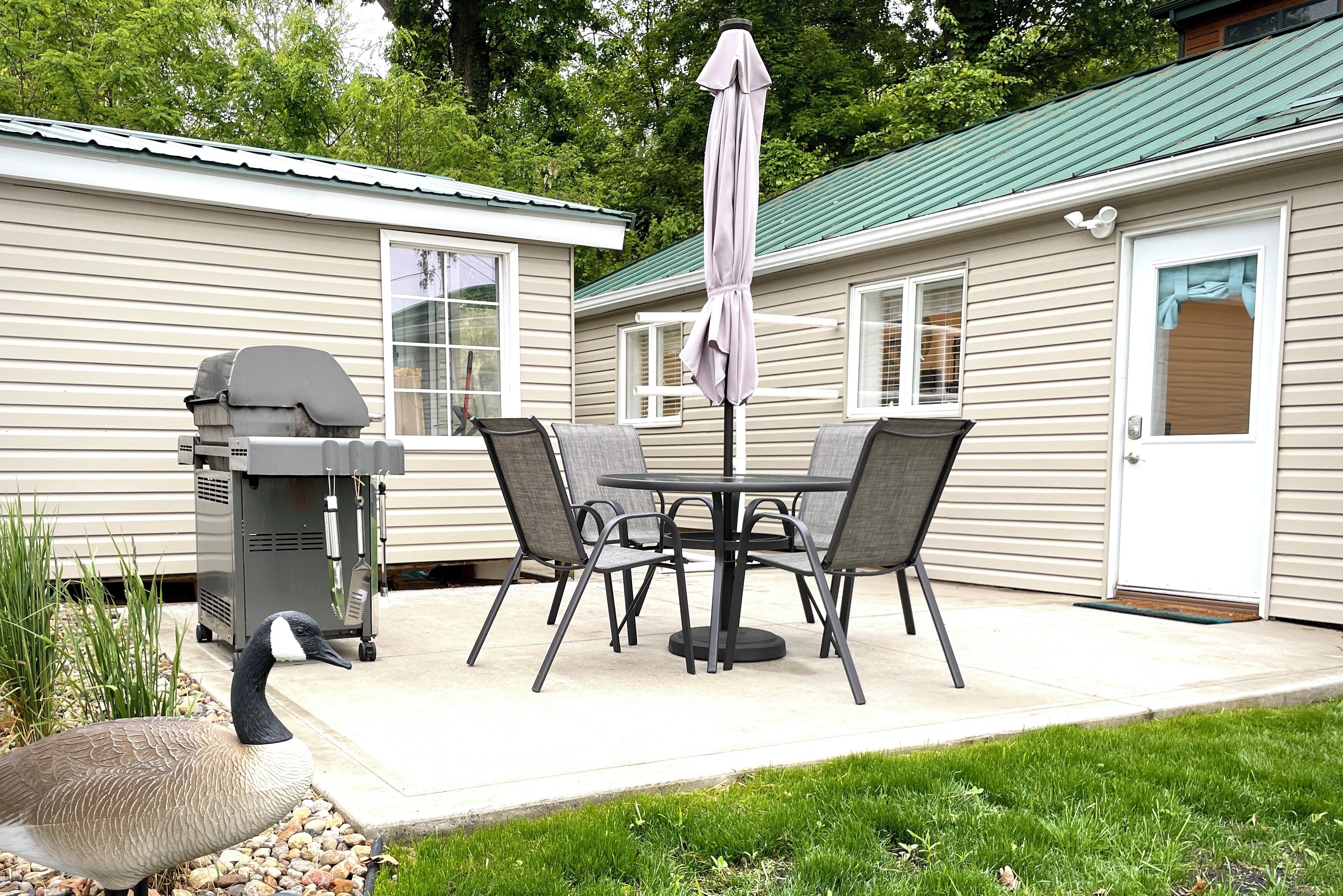 Une terrasse avec un barbecue, une table et des chaises.