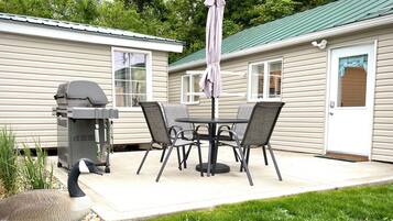 Une terrasse avec un barbecue, une table et des chaises.