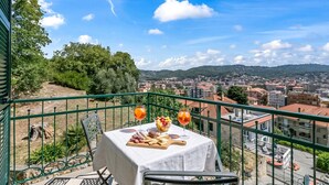 A balcony with a table set for a meal, a city view, and a clear sky. - Seaview Pool Retreat - B28, Andora, Italy (Andora)