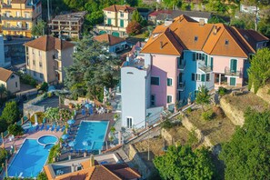 Vista aérea de uma área residencial com piscina, várias casas e uma encosta.