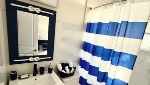A bathroom with a white sink, dark cabinets, a white toilet, and a blue and white striped shower curtain.