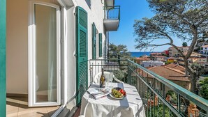 En balkon med et bord dækket til to personer, en flaske og en frugtfat.