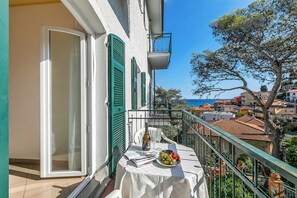 Ein Balkon mit Tisch für zwei Personen, einer Flasche und einer Obstplatte.
