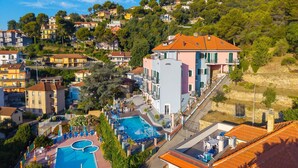 Ett bostadsområde på en sluttning med en pool, balkonger och en variation av fasadfärger.