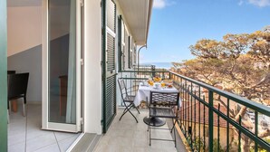 Un balcon avec une table préparée pour le petit-déjeuner, une chaise et un téléviseur.
