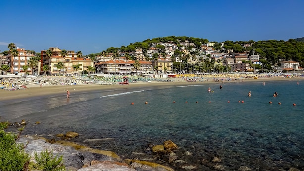 Un pueblo costero con playa, aguas cristalinas y edificios con balcones.