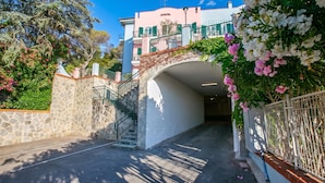 Un sendero de piedra que conduce a un edificio con un arco blanco, una escalera y una barandilla de metal.