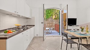 Une cuisine moderne avec des meubles blancs, une cuisinière à gaz et un coin repas comprenant une table et des chaises.