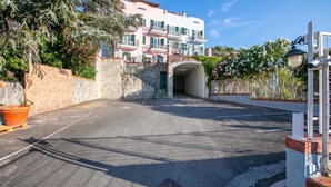 A multi-story building with balconies, a stone wall, and a paved entrance area. - Seaview Pool Retreat - B1, Andora, Italy (Andora)