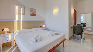 Ett hotellrum med en säng, sängbord, en stol, ett skrivbord och en matplats.