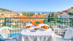 Ein Tisch mit Speisen und Getränken auf einem Balkon mit Blick auf eine Küstenstadt.