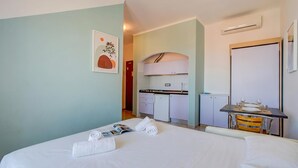 Ein Hotelzimmer mit Bett, einer kleinen Küchenzeile, einem Esstisch mit Stühlen und einer Tür.