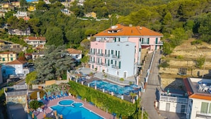 Ein mehrstöckiges Hotel mit Schwimmbad, Balkonen und Blick auf eine Hügelterrasse.