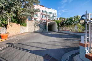 A multi-story building with balconies, a stone wall, and a paved entrance area. - Seaview Pool Retreat - M16, Andora, Italy (Andora)