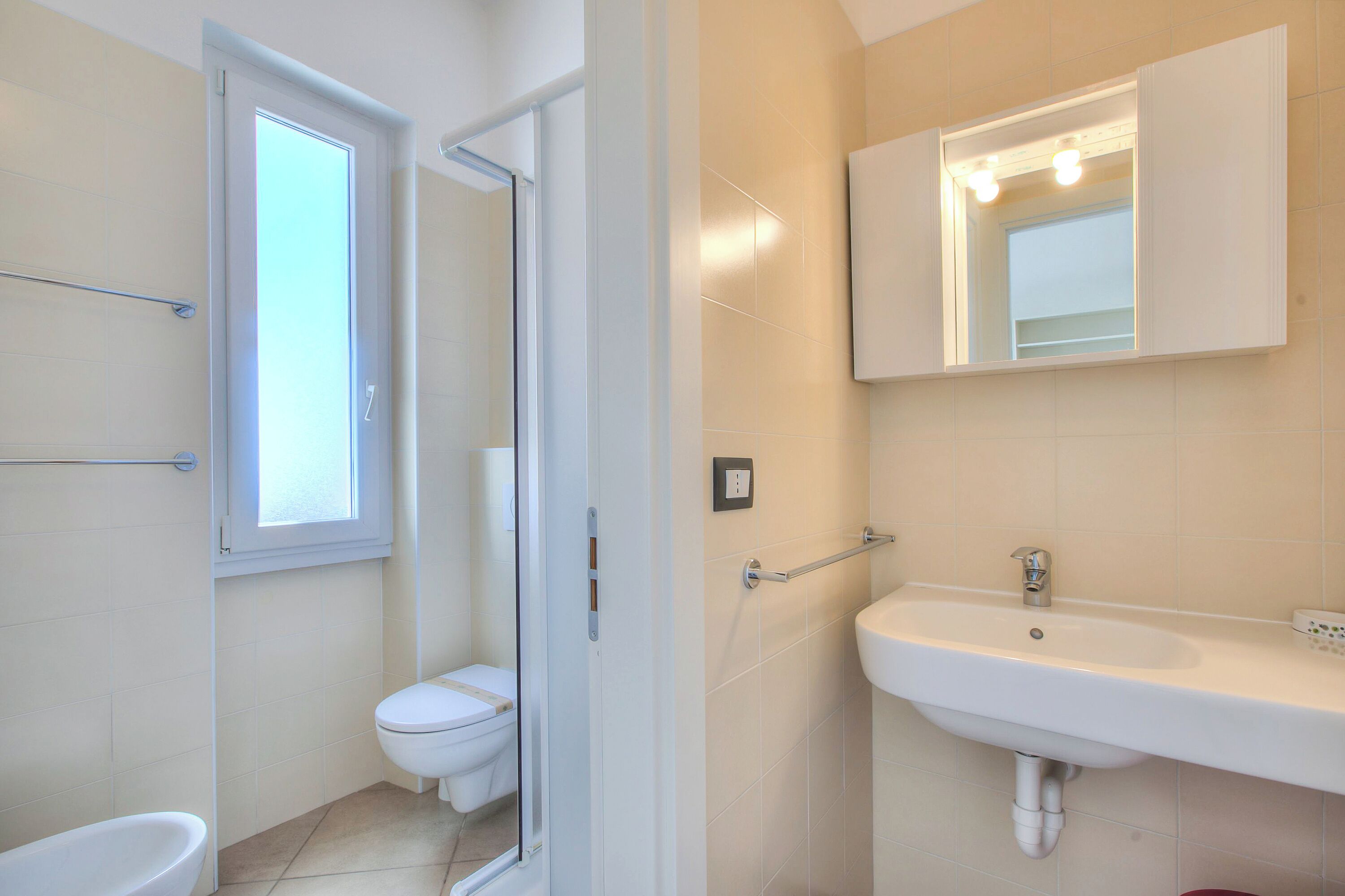 Une salle de bain comprenant des toilettes, un lavabo, un miroir et une douche.