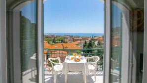 A balcony with a table set for breakfast, overlooking a cityscape and the sea. - Seaview Pool Retreat - M19, Andora, Italy (Andora)