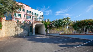 Un espace de stationnement menant à un bâtiment doté d’une façade en pierre et d’un escalier.
