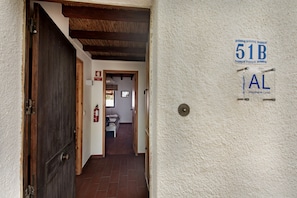 Un couloir avec une porte en bois, un extincteur et un panneau indiquant le numéro de la pièce : 51 B.