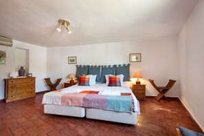 A bedroom with a large bed, wooden nightstands, a dresser, and a ceiling light fixture.