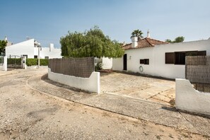 A residential area with white houses, a paved courtyard, and a tree.