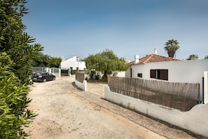 Un quartier résidentiel avec des maisons blanches, une allée gravillonnée et une voiture garée.