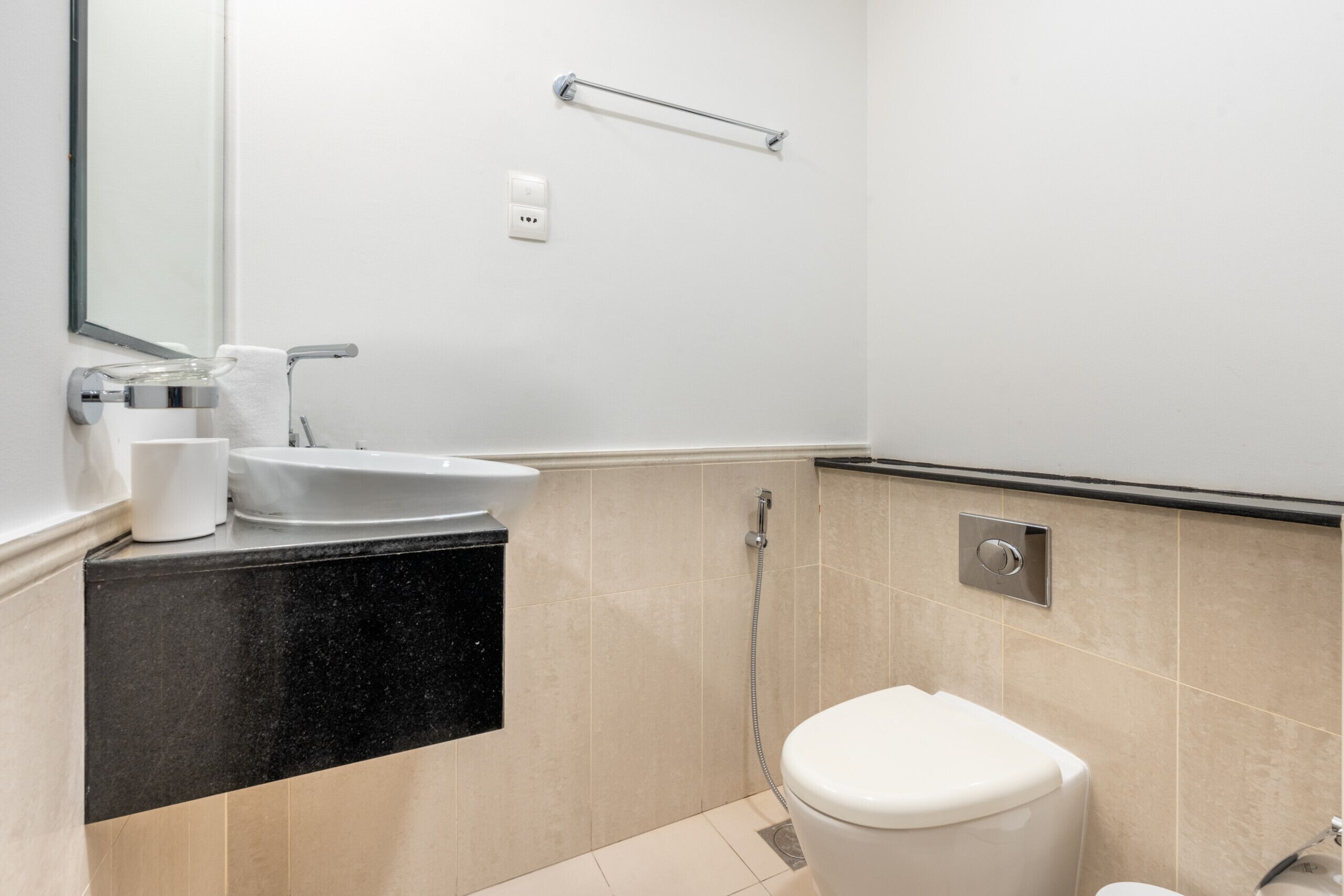 Ein modernes Badezimmer mit Waschbecken, Spiegel, Handtuchhalter und Toilette.