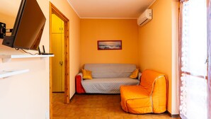 A compact room with a sofa, a chair, a television on a stand, and a painting on the wall. - Casa Anna by Interhome (Pompeiana)