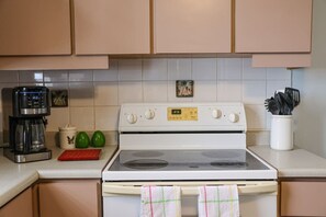 A kitchen with a stove, coffee maker, and a small decorative item on the wall. - Oasis LifeStyle Beach & a Pool (Rincón)