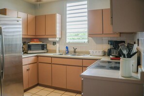 A kitchen with a stainless steel refrigerator, a microwave, a toaster, and a sink.
