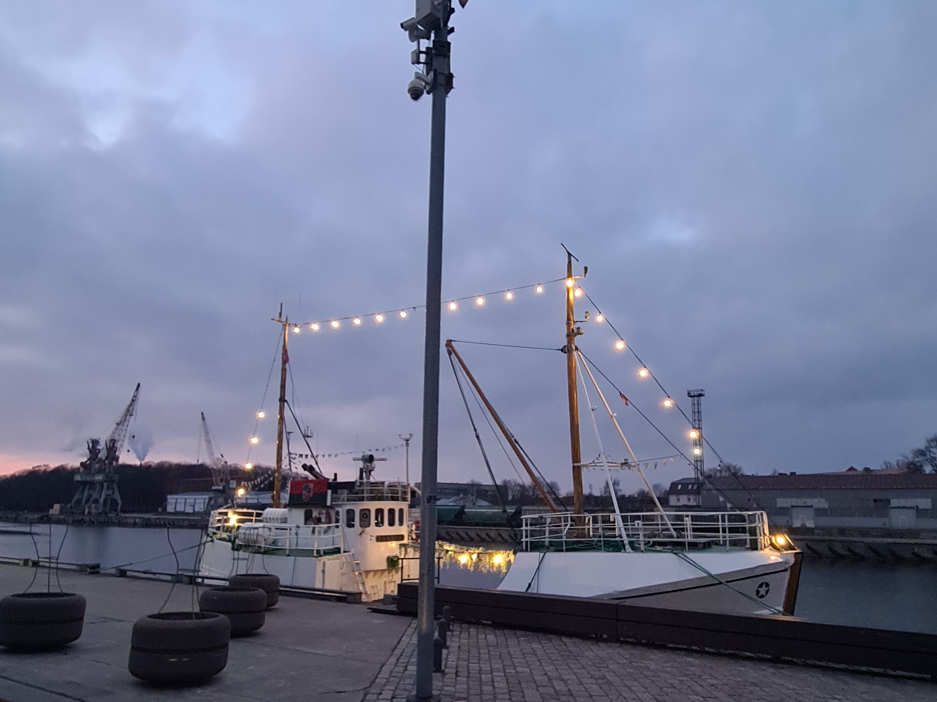 A dock with a boat, a crane, and a streetlight.