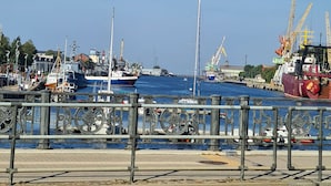A harbor with boats, cranes, and a dock.