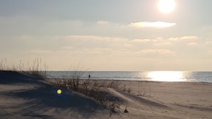 A beach with a clear sky and the sun low on the horizon.