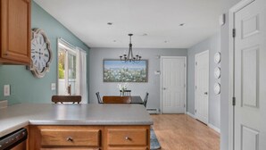 A kitchen with wooden cabinets, a granite countertop, and a dining area with a table and chairs.