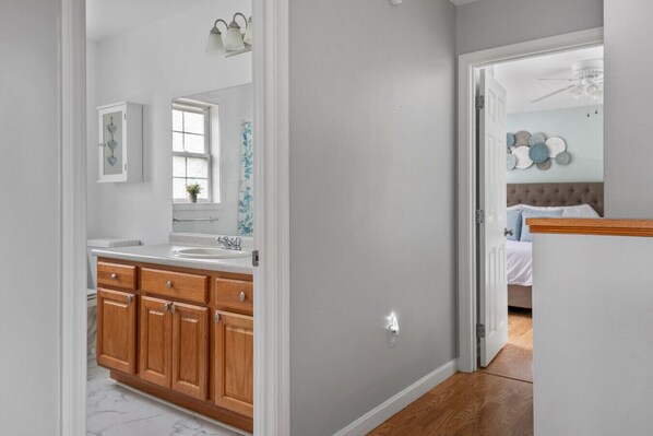 A modern bathroom with a wooden vanity, a large mirror, and a window.