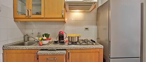Una cocina con armarios de madera, un lavamanos de acero inoxidable, un microondas y un refrigerador.