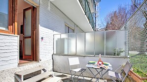 Een terras met een tafel, stoelen en een bank.