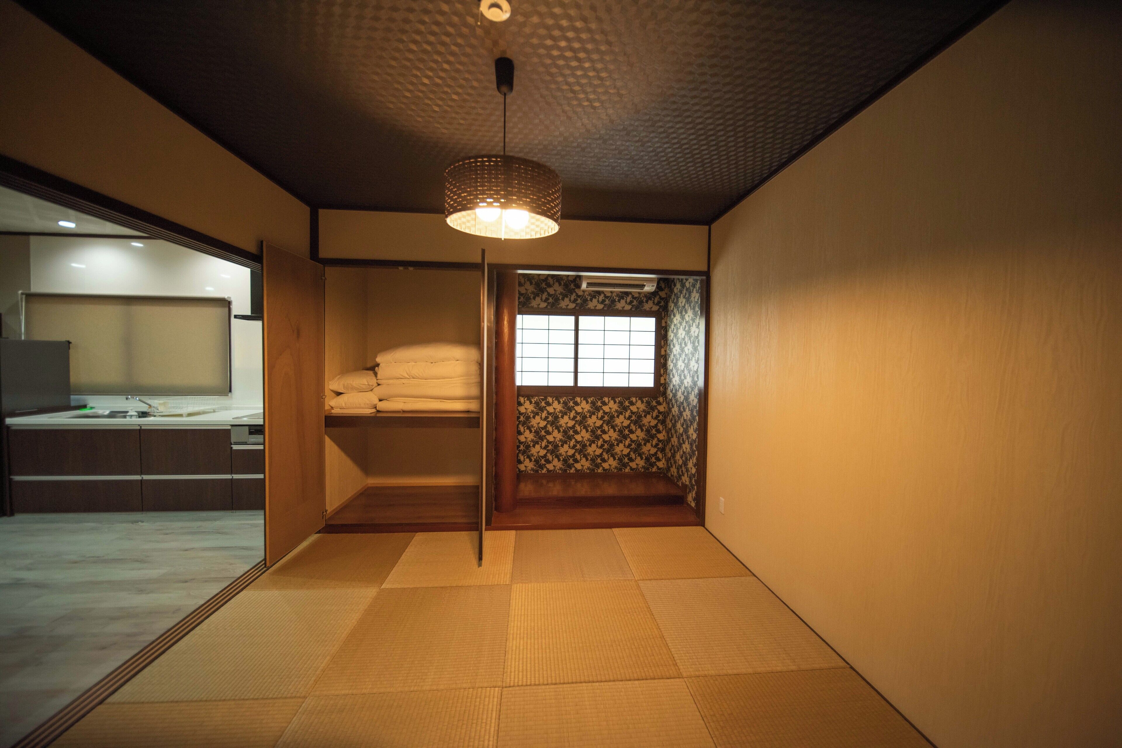 Um quarto japonês tradicional com piso de tatame, porta deslizante e luminária pendente.