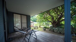 Una terraza de madera con una hamaca, una mesa de picnic y un muro de piedra.