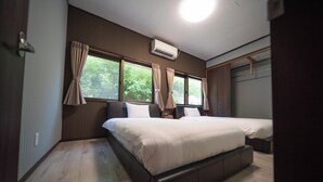Un dormitorio con dos camas, piso de madera y ventana con cortinas.