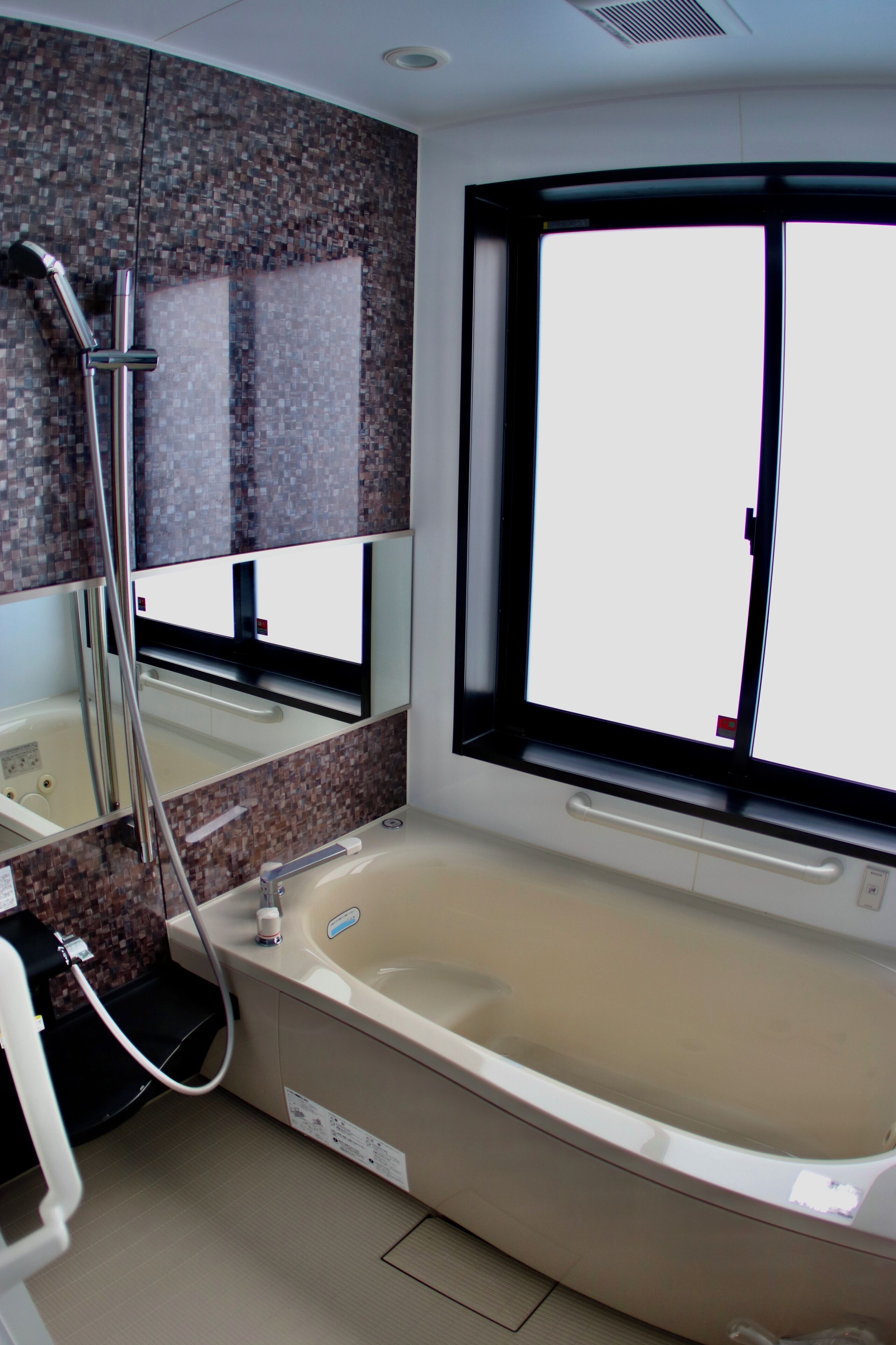 A bathroom with a large bathtub, a shower, a mirror, and a window.