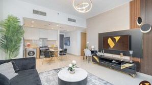 A modern living room with a black sofa, a round coffee table, and a TV mounted on the wall. - Vogue | Harbour Views Creek Harbour | Waterfront living (Dubai)