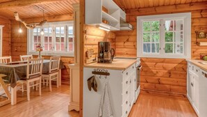 L’intérieur d’un chalet en bois comprend un coin repas, une cuisine et de grandes fenêtres.