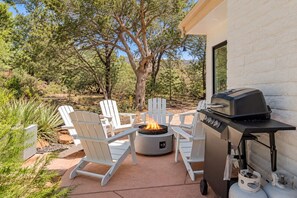 An outdoor patio with a fire pit, white Adirondack chairs, and a portable grill. - Serene Family Friendly Sedona home /private HotTub (Sedona)