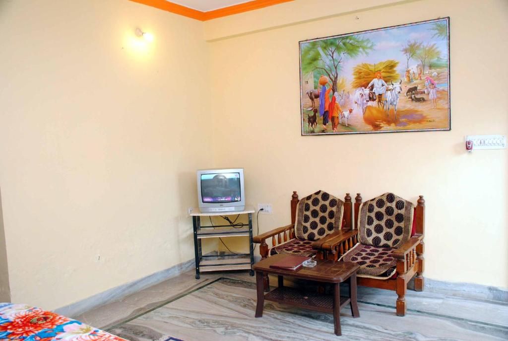 Una habitación con un conjunto de sofás, un televisor sobre un mueble bajo y un cuadro en la pared.
