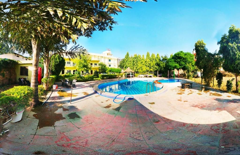 Piscina com um deck ao redor, um gazebo e um prédio ao fundo.