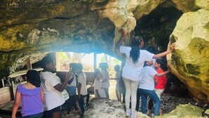 A group of people exploring a cave with natural rock formations and a wooden structure inside.