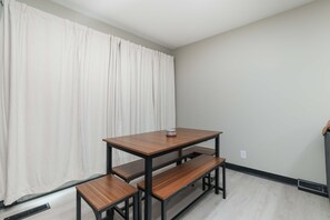 A room with a wooden table and benches, a white curtain, and a light-colored floor. - Dazzling East Side 3BR 2 BA Coffee/WFI/SMRT TV (Wichita)